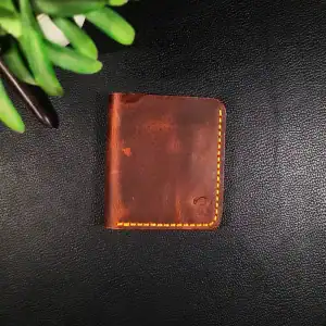 Leather vertical smart wallet with yellow stitching on black background.
