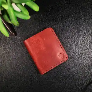 Red leather vertical smart wallet on black surface with green plant.